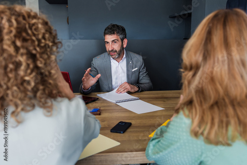 hispanic senior businessman or adult manager working and talking to his colleagues at workplace
