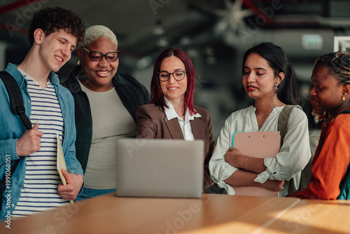 Fotografie Diverse group of multi ethnic students and a female teacher gathering around a l