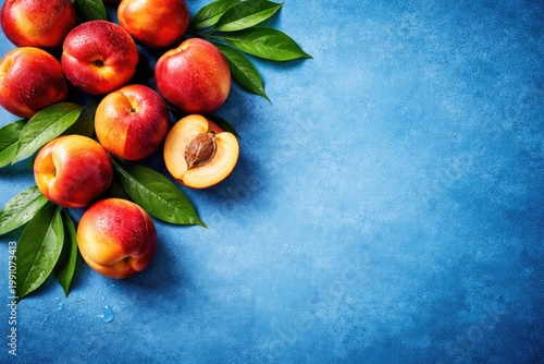 Top view of ripe nectarine with leaves on blue background with copy space
