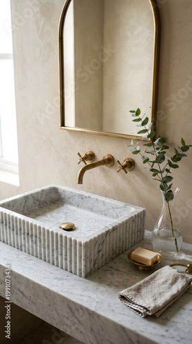 Elegant bathroom sink with marble basin and brass fixtures set against a neutral wall