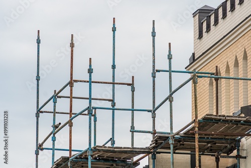 Scaffolding structure in an ongoing urban construction, with building materials and a multi-story building under construction Overcast daytime lighting
