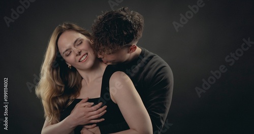 Obraz na płótnie Young couple embracing passionately against a dark background, showing love and