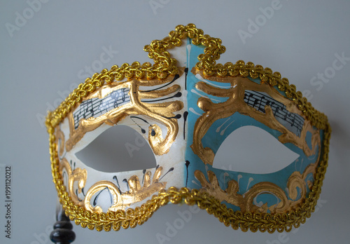 Decorative Venetian carnival mask with gold ornaments blue and white pattern and musical notes detail. Elegant theatrical accessory for masquerade celebration isolated on light background.