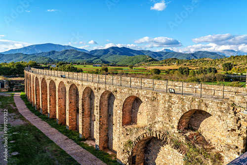 Ainsa Castle in the medieval village of Ainsa in Spain surrounded by stone walls with an elevated path leading to it.