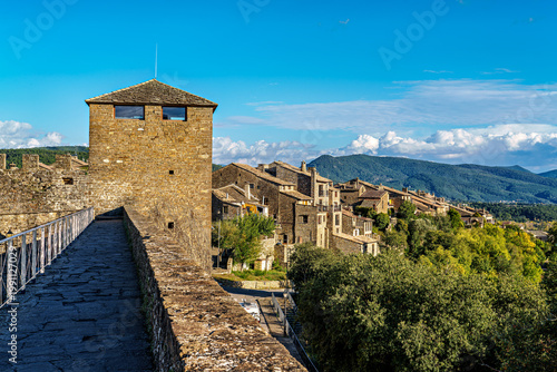 Ainsa Castle in the medieval village of Ainsa in Spain surrounded by stone walls with an elevated path leading to it.