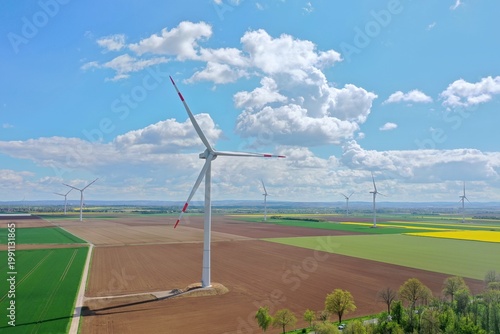 Aerial view, Yellow Flower Field with Wind Turbines under Blue Sky – Clean Energy