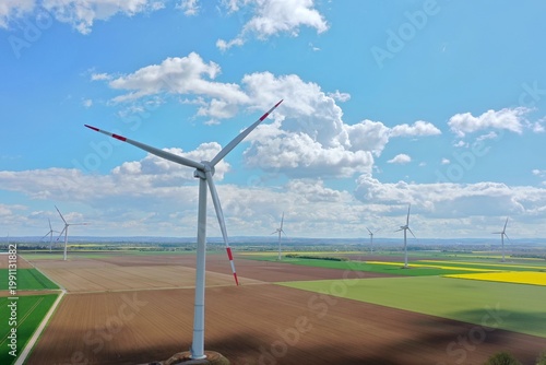 Aerial view, Yellow Flower Field with Wind Turbines under Blue Sky – Clean Energy