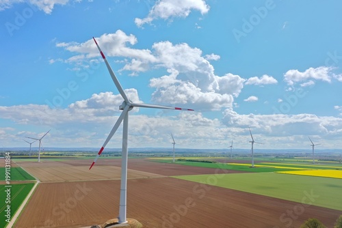 Aerial view, Yellow Flower Field with Wind Turbines under Blue Sky – Clean Energy
