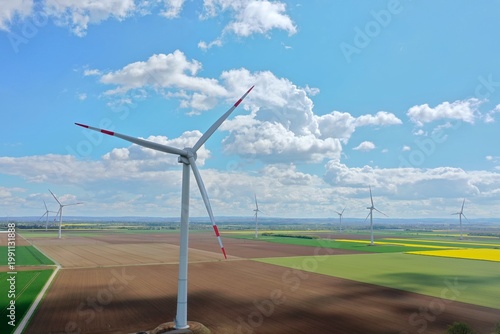 Aerial view, Yellow Flower Field with Wind Turbines under Blue Sky – Clean Energy