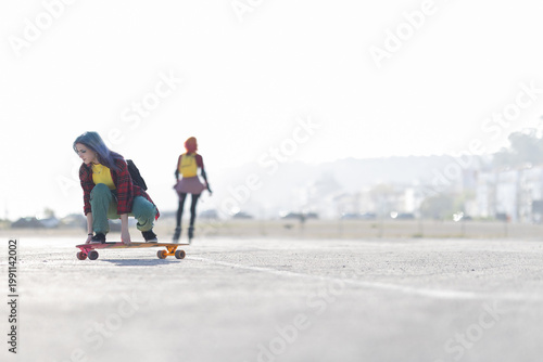 Photos Young woman crouching on skateboard preparing to ride