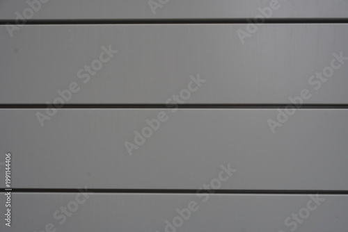 Bild auf Leinwand Close-up of modern architectural cladding featuring horizontal grey metal panels with clean, dark recessed shadow gaps