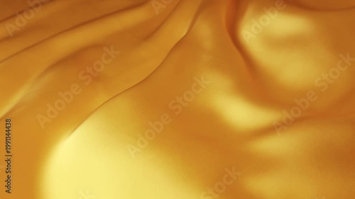 Abstract golden natural silk fabric waving in the wind. Smooth elegant flowing waves creating a luxury background. Seamless motion of yellow and orange soft textile.
