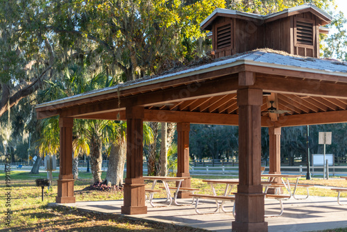 Quadro su tela A large four-sided wooden gazebo overlooking a park with tall trees