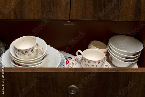 Open kitchen cabinet drawer with neatly arranged crockery and organized storage interior