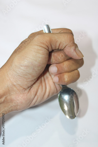 Hand grips spoon tightly against white background