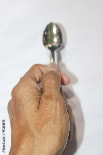 Hand grips spoon against a clean white background