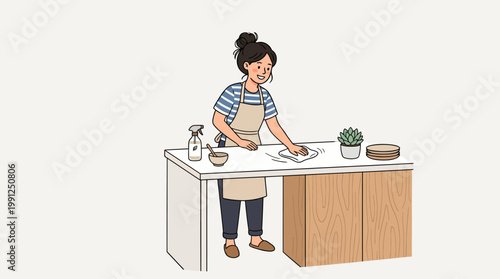 Smiling young woman in apron wiping and cleaning kitchen counter with cloth