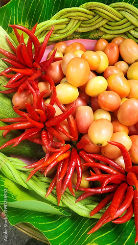 Colorful assortment of fresh vegetables in a tray: red chili peppers, tomatoes, cucumbers, and yardlong beans for somtam. Vibrant Thai street food market display highlighting freshness and healthy ing