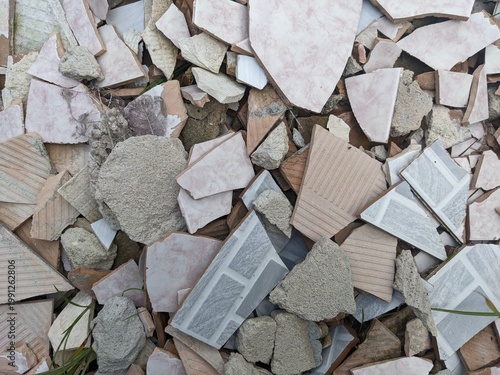 Pile of broken ceramic and porcelain tiles, fragments of decorative and plain tiles scattered, construction debris, renovation waste material, and home improvement remnants