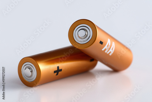 Two copper AA alkaline batteries on a white reflective background, portable energy and power supply concept