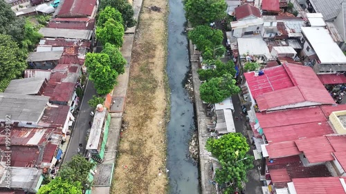 An blue excavator is working to digging the bottom of the jakarta river, Excavator with a long arm.  floating platform in a river digging cumulative dirt that shallowing the river