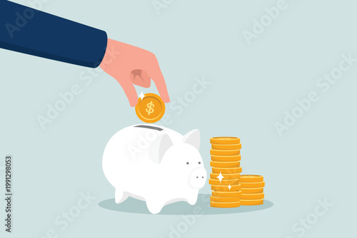 Business or financial concept, the hands of entrepreneurs save by putting coins into a piggy bank with a pile of coins beside it.