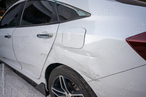 White car side with visible rear door damage and scratches on body panel