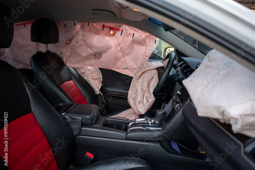 Photos Deployed airbags inside modern car interior with black and red seats