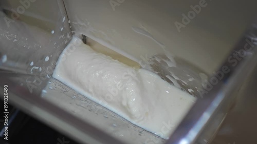 Gelato machine dispensing creamy gelato into a container. Ice cream making process.