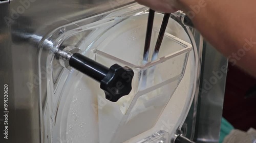 Gelato machine dispensing creamy gelato into a container. Ice cream making process.