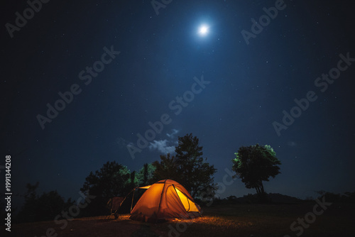 nature traveling with orange camping tent on mountain with milky way and star background