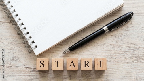 白いノートとペン、そして「START」と並べられた木製ブロックが、新しい目標への第一歩や挑戦の始まり、計画立案、学習開始、自己成長への意欲を表現するシンプルなコンセプトイメージ。新生活、新年度、勉強、仕事、自己啓発、行動喚起の広告や販促物に適した清潔感のある素材