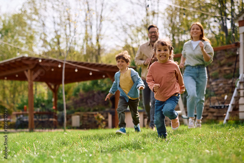 Foto Carefree girl and her family having fun while running in spring day outdoors