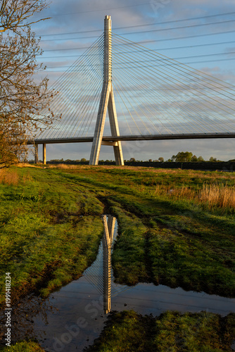 Flintshire bridge concrete support tower and steel cables mirrored in still River Dee estuary pool