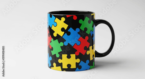 A colorful puzzle piece design on a ceramic coffee mug sits on a white surface indoors.
