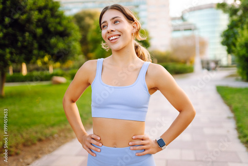 Tableau sur toile A happy woman stands in a sunny park after a workout