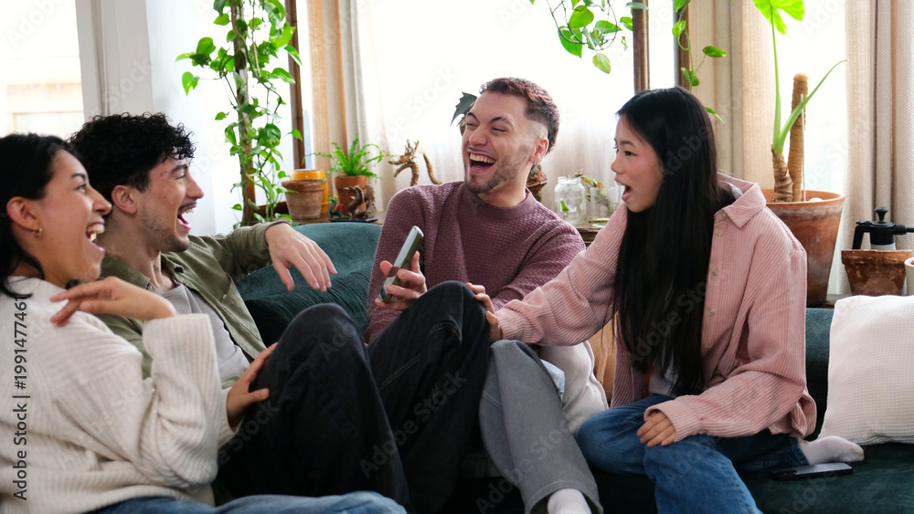 Obraz premium Group of happy young friends enjoying shared content on a mobile phone on a couch at home