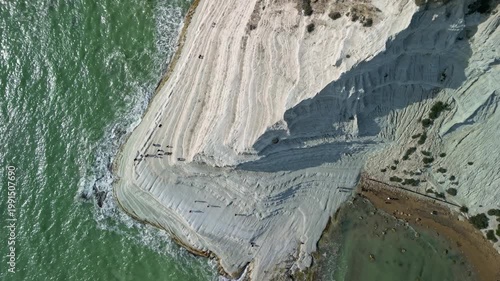 Aerial view of people walking along the unique white rock formations by the turquoise sea, showcasing the stunning coastal landscape and natural beauty of the region