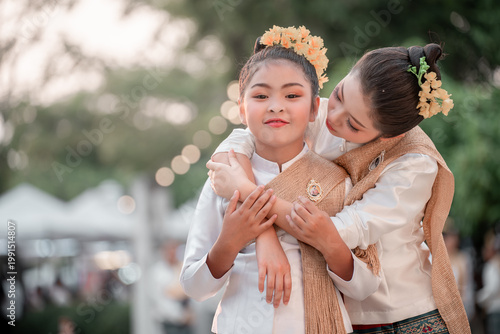 Young Girls in Traditional Attire Embrace in Outdoor Festival Scene
