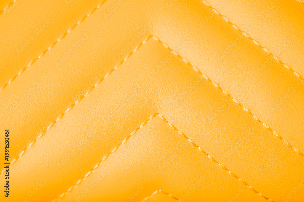 Obraz premium Detailed view of vibrant yellow quilted leather texture with diagonal stitching pattern close up