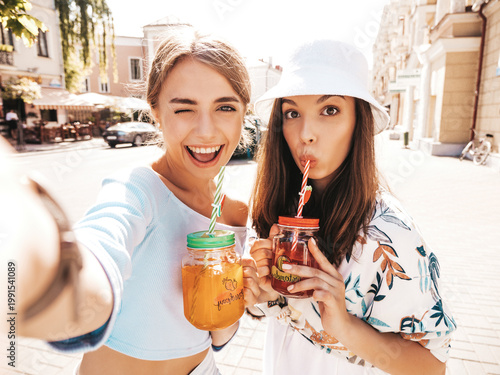 Fotografie Two young beautiful smiling hipster in trendy summer clothes