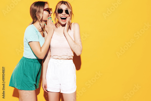 Foto Two young beautiful smiling brunette hipster female in trendy summer clothes