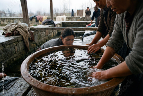 Women dyeing fabric in a large vat during textile work in an outdoor craft setting with vivid industrious energy