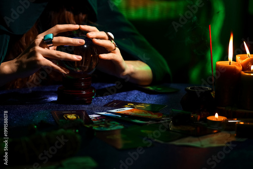 Photography Fortune teller with crystal ball and tarot cards at table in dark room, closeup