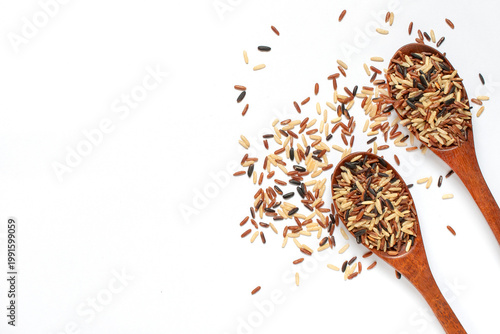 Top view of uncooked rice varieties in wooden spoons, isolated on a white background with copy space. Concept of natural food, agriculture, organic ingredients, and healthy eating.