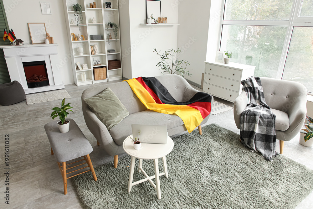 Fototapeta premium Interior of light living room with German flag on sofa and armchair