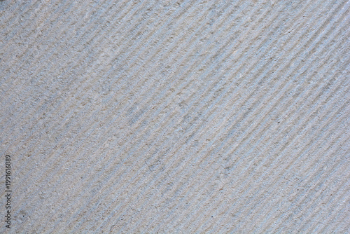 A close up of a gray stone surface with fine diagonal chiseled lines and a rough granular texture