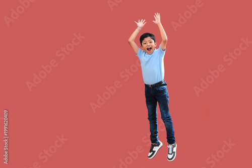 9-year-old Latino boy with dark skin jumps for joy to celebrate his excitement