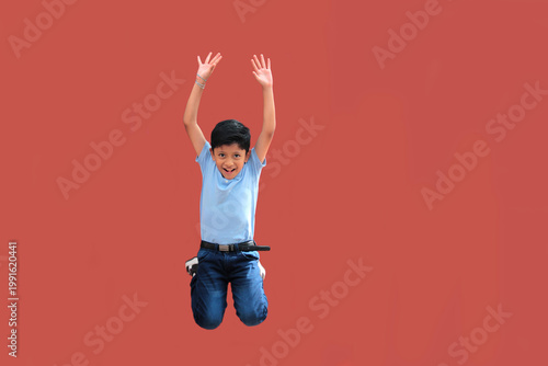 9-year-old Latino boy with dark skin jumps for joy to celebrate his excitement