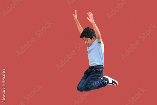 9-year-old Latino boy with dark skin jumps for joy to celebrate his excitement